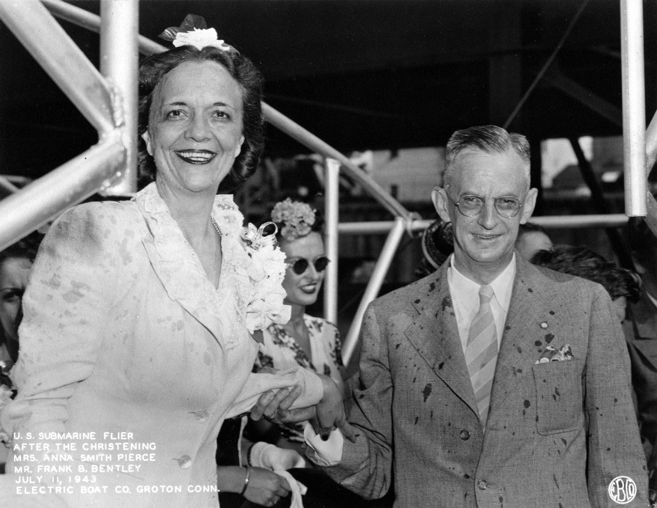 Mrs. Anna Smith Pierce and Mr. Frank B. Bentley smile after being showered with champagne at Flier’s christening at New London, 11 July 1943. (U.S. Navy Photograph 80-G-77833, National Archives and Records Administration, Still Pictures Division,...