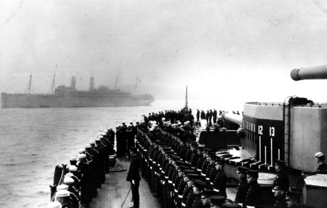 Ship's crew manning the rail as George Washington (in background) enters Brest harbor, France, with President Woodrow Wilson on board, 13 December 1918. Note marines in the center foreground, and bearing markings painted on her 12-inch gun turret side. (Collection of Adm. Montgomery M. Taylor, 1962, Naval History and Heritage Command Photograph NH 78103).