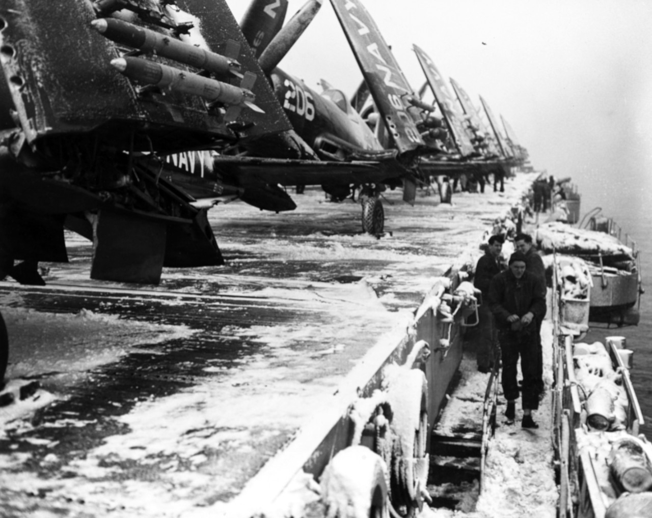 The ships of the task force fight in bitter winter weather but crewmen take a break and participate in a snowball fight while clearing snow from Valley Forge’s flight deck in Korean waters, early 1951. The planes parked on the deck are Vought F4F...