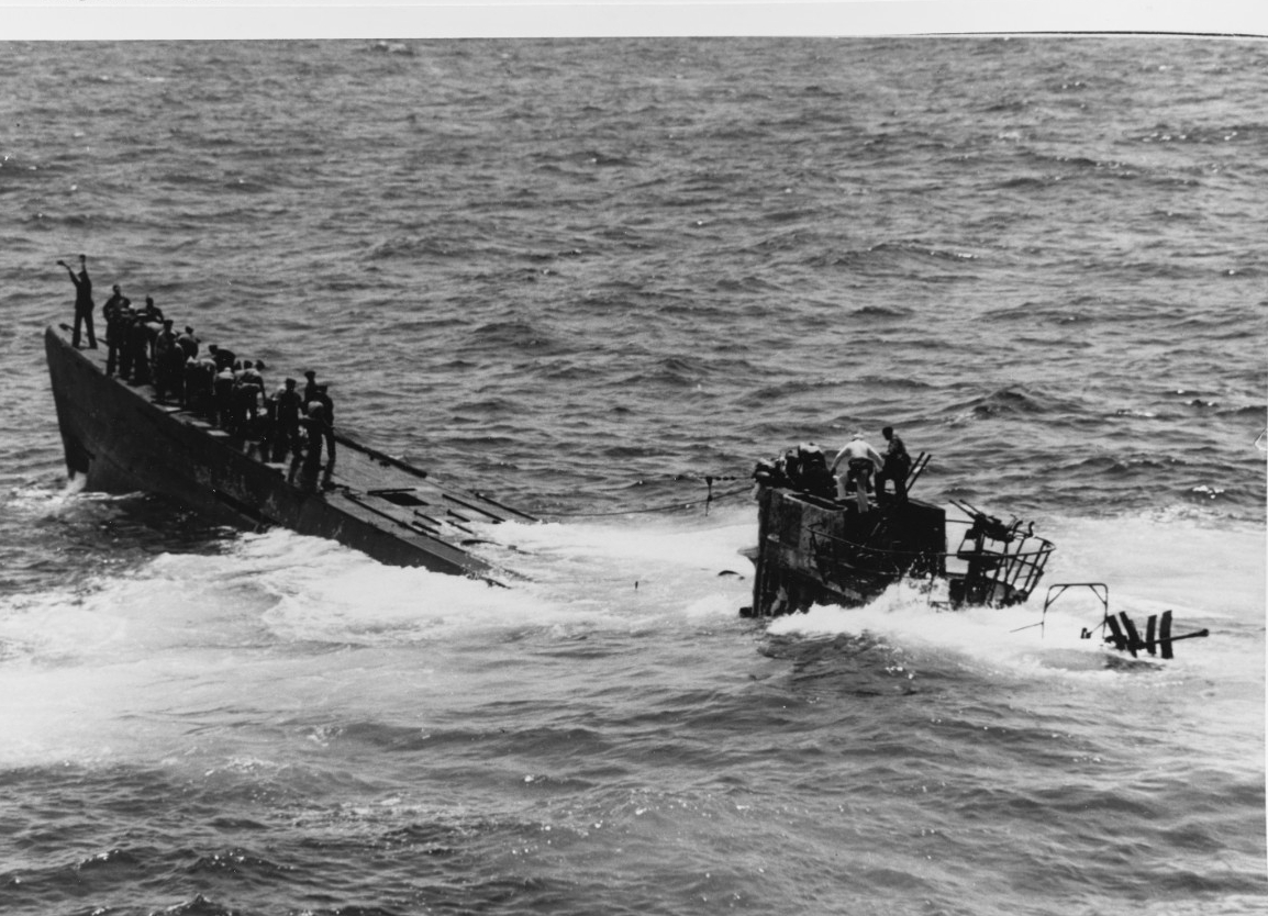 A port quarter view of U-505 shows the boat wallowing as the boarders continue their fight to save her. Some of the Americans move forward to secure a tow line, while others man the conning tower, in addition to those working below. Photographed ...