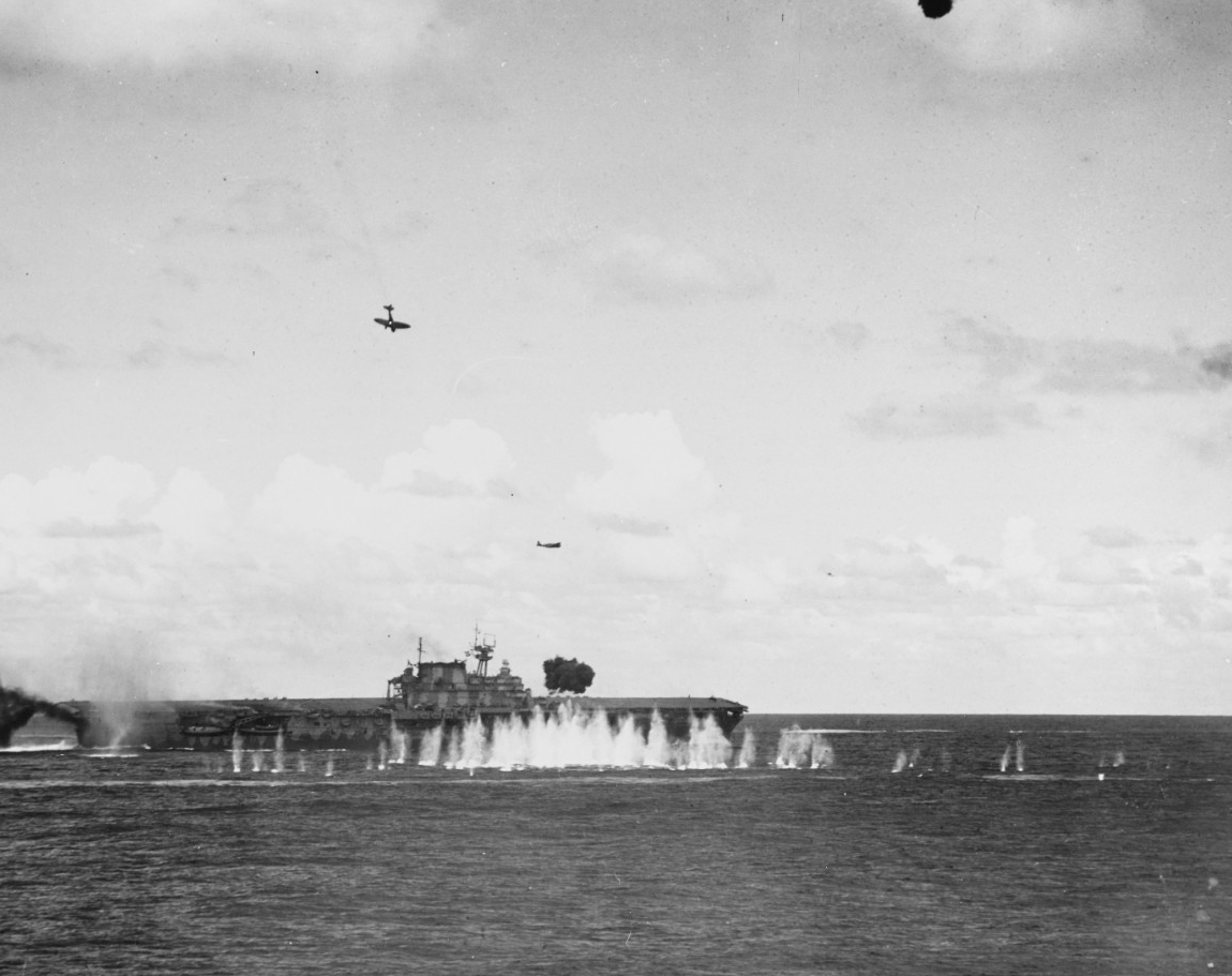 Japanese planes swamp Hornet’s defenses at the Battle of the Santa Cruz Islands, 26 October 1942. An Aichi D3A1 Type 99 carrier bomber hit by U.S. fire trails smoke and hurtles toward the ship, and is about to smash into the carrier’s stack and t...