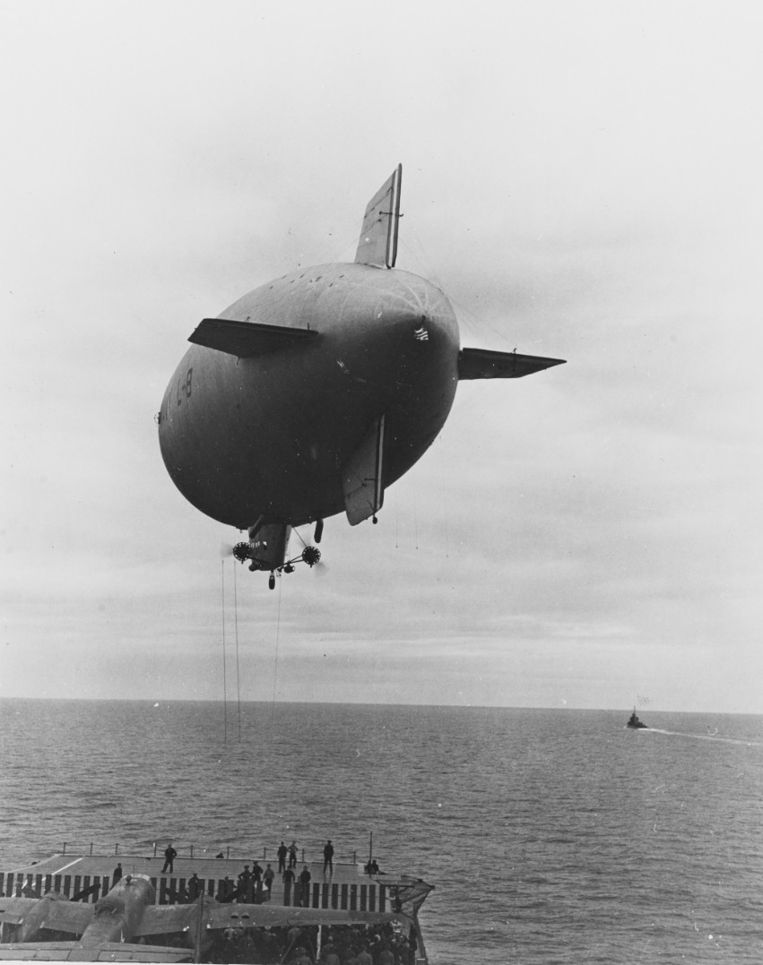 Navy blimp L-8 hovers over Hornet’s flight deck as she delivers vital navigator’s domes for the North American B-25B Mitchells, 2 April 1942. (U.S. Navy Photograph NH 53294, Naval History and Heritage Command)