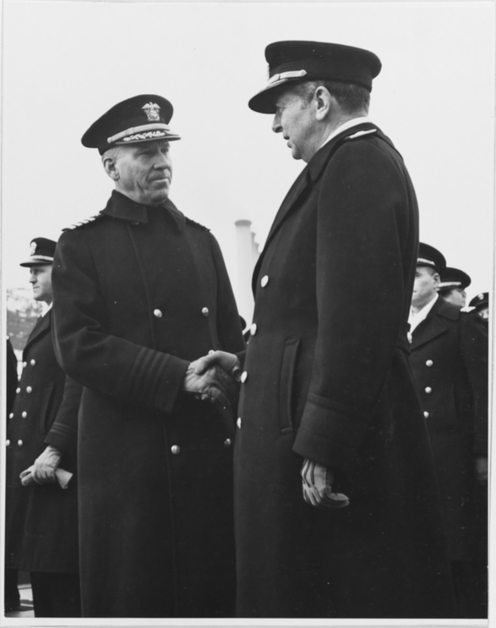 Rear Adm. Adolphus Andrews, Commandant, Third Naval District, congratulates Capt. Lyman K. Swenson (left), the ship’s commanding officer, at Juneau’s commissioning. (Naval History and Heritage Command Photograph NH 52360)