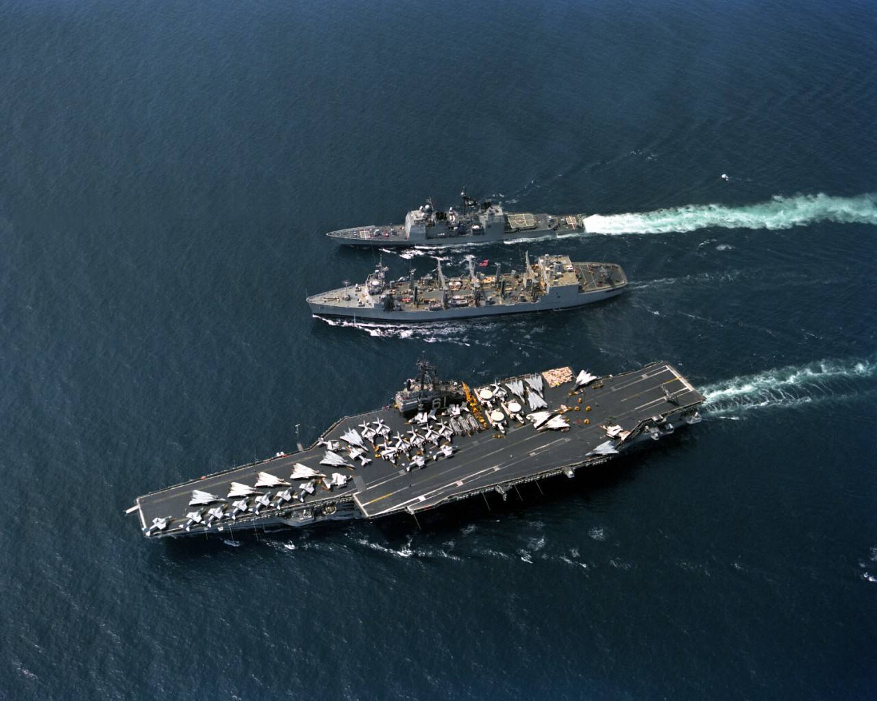 The aircraft carrier Ranger (CV-61) turns to port after completing an underway replenishment with Kansas City as the guided missile cruiser Valley Forge (CG-50) takes on fuel from the replenishment oiler, 28 March 1991. (U.S. Navy Photograph DN-S...