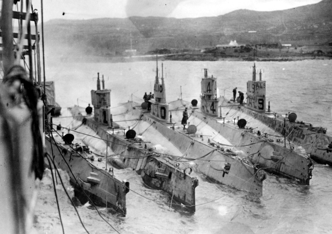 AL-type submarines alongside what is probably Bushnell (Submarine Tender No. 2) at what is most likely Berehaven, Ireland. Submarines are (from left to right): L-3; L-11; L-10; L-4; and L-9. Note the differing forms of chariot bridges on these su...