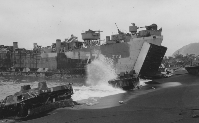 As waves crash against beached LVTs (the one in the foreground, 5A-30, named FELICE), LST-779 unloads at Iwo Jima, 26 February 1945. Suribachi looms in the background (R). Note weathered camouflage and duplicate identification numbers.  (U.S. Navy Photograph 80-G-317961, National Archives and Records Administration, Still Pictures Branch, College Park, Md.)