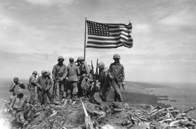 Risking sniper fire, marines gather around LST-779’s colors as they snap in the wind at the summit of Suribachi, 23 February 1945, as photographed by Pvt. Bob Campbell, USMC. (U.S. Marine Corps Photograph RG-127-GW-319-112721, National Archives and Records Administration, Still Pictures Branch, College Park, Md.)