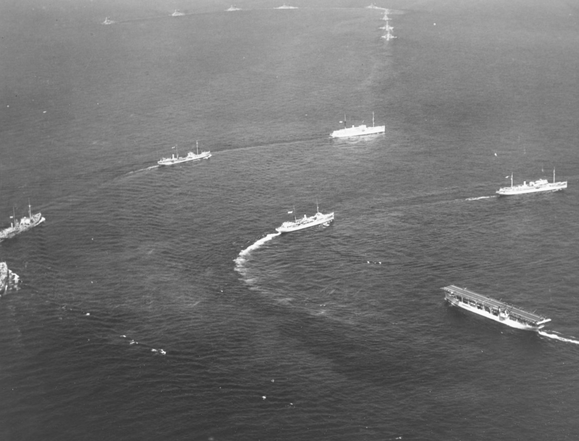 Ships of the Fleet Train maneuver during the fleet review off New York, 31 May 1934. Melville (right center) crosses the bow of Langley (CV-1), led by either Dobbin (AD-3) or Whitney (AD-4). Hospital ship Relief (AH-1) leads the next line, follow...