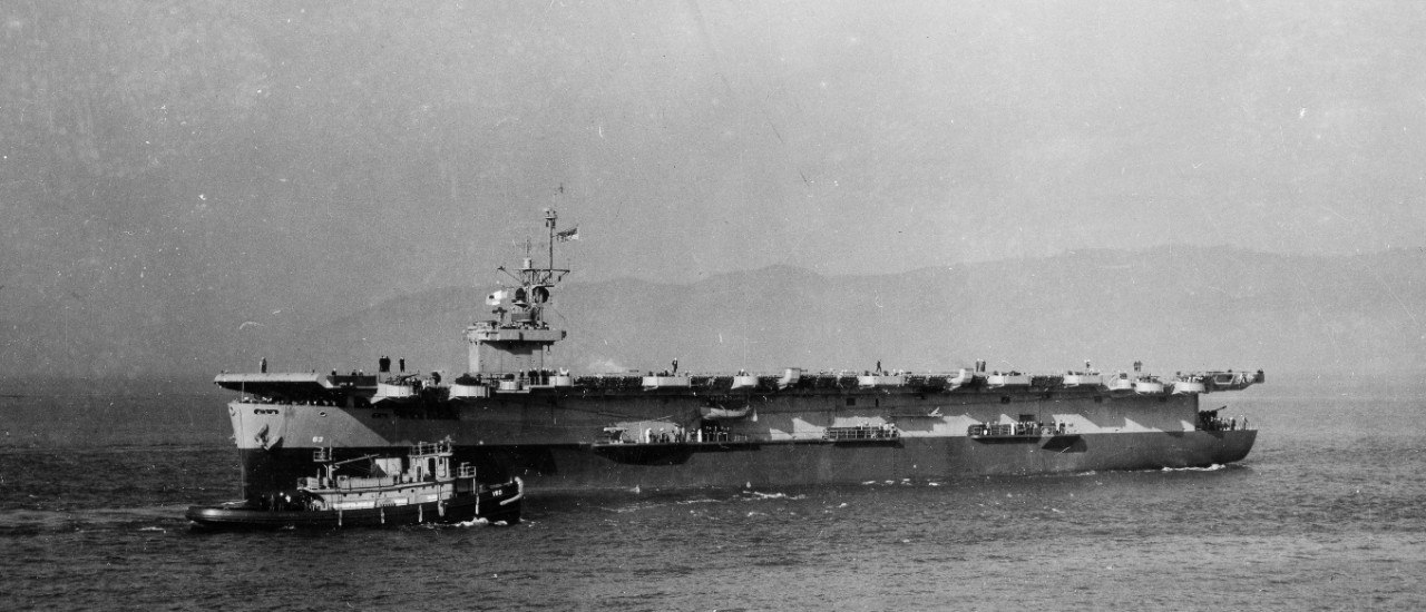 Midway, wearing the two-color camouflage originally applied to her, the dividing line running parallel to the horizon and not to the sheer of the main deck, backs down off Astoria as seen from sister ship Tripoli (CVE-64), 13 November 1943. Harbo...