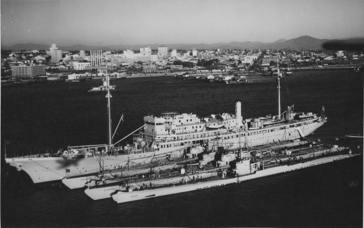 Nautilus undergoes a tender availability alongside Holland in San Diego Harbor, 10 November 1932, nested to the auxiliary vessel’s port side. Also visible are Nautilus’s sister Narwhal (N-1), and Bass (SS-164) (B-2). Ship whose identification num...