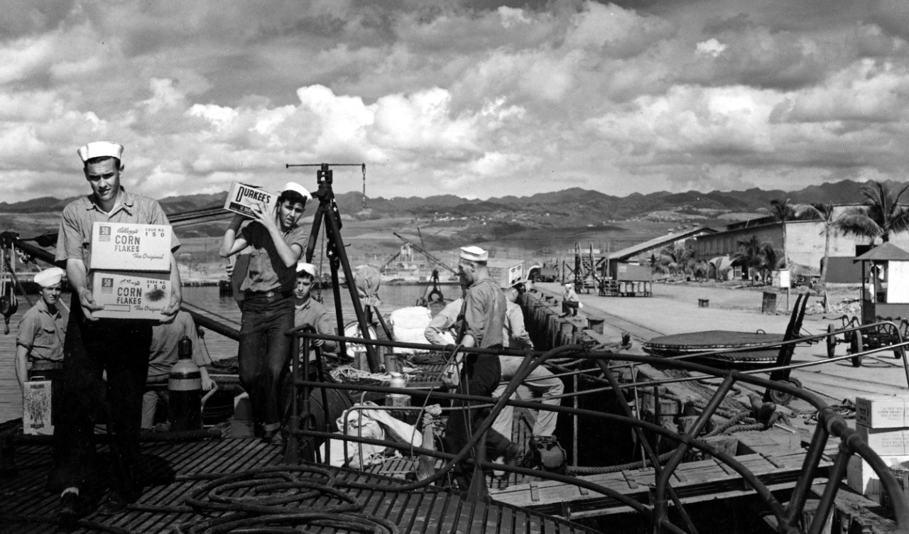 Nautilus provisions at Pearl Harbor, 11 December 1942, as she prepares for her fourth war patrol, the sailors at left carrying boxes of Kellogg’s Corn Flakes and Durkee’s Mayonnaise. This view looks toward the bow from the deck near Mt. 61. (U.S....