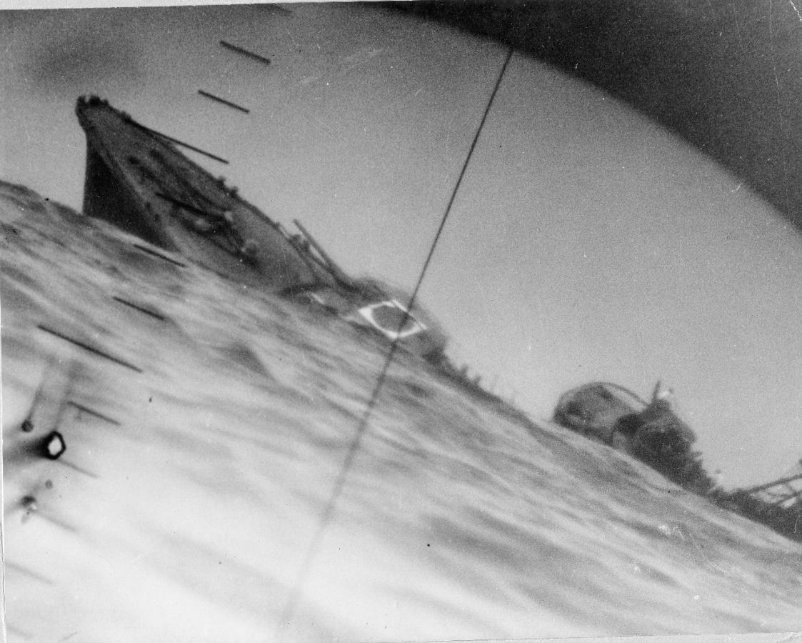 Seen through Nautilus’s periscope, Yamakaze heels to port and sinks by the stern, the Japanese ship’s red and white aerial recognition marking clearly visible on the roof of her forward 5-inch/50 mount. This stark image of the doomed destroyer be...