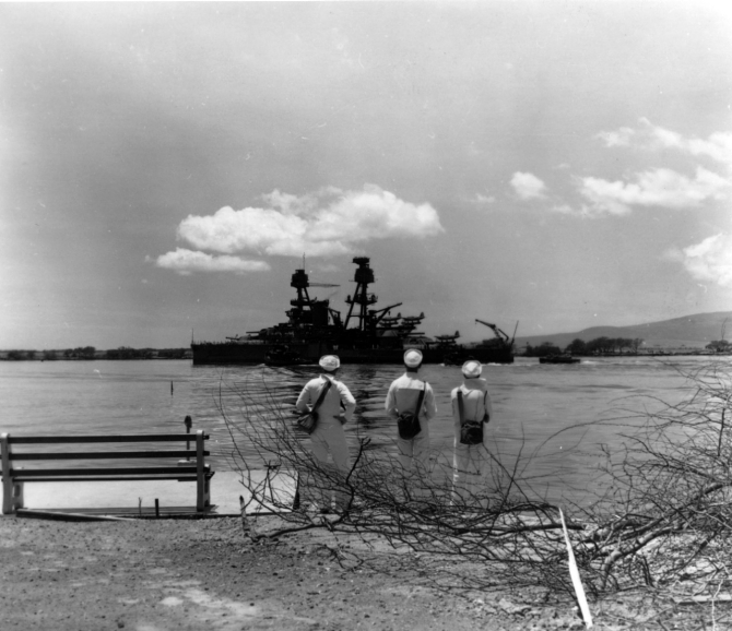 Nevada departing Pearl Harbor after temporary repair of bomb and torpedo damage received during the Japanese air raid on 7 December 1941. Photograph is dated 19 April 1942, possibly taken as the ship was leaving for a trial run. Note sailors watching, each carrying a gas mask container. Photographed by Photographer’s Mate 2nd Class H.S. Fawcett. (U.S. Navy Photograph 80-G-64768 National Archives and Records Administration, Still Pictures Division, College Park, Md.)