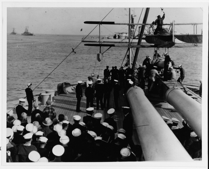 American humorist Will Rogers (hatless, in center) talks with some of the ship's officers on the quarterdeck, on board Pennsylvania, March 1928. Note men at right placing a Vought UO-1 aircraft on the catapult. Courtesy of the Naval Historical Foundation, Collection of Adm. Montgomery M. Taylor. (Naval History and Heritage Command Photograph NH 42749) 