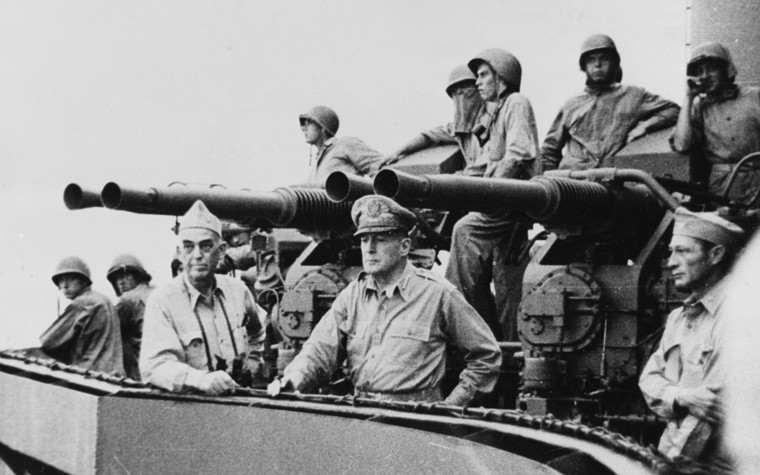 Vice Adm. Kinkaid (left center) and Gen. MacArthur (center) watch the ship bombard the Japanese on Los Negros, 28 February 1944. Col. Lloyd Lehrbas, USA, MacArthur’s acting aide, is on the right. Note the quad 40-millimeter gun mount in the backg...