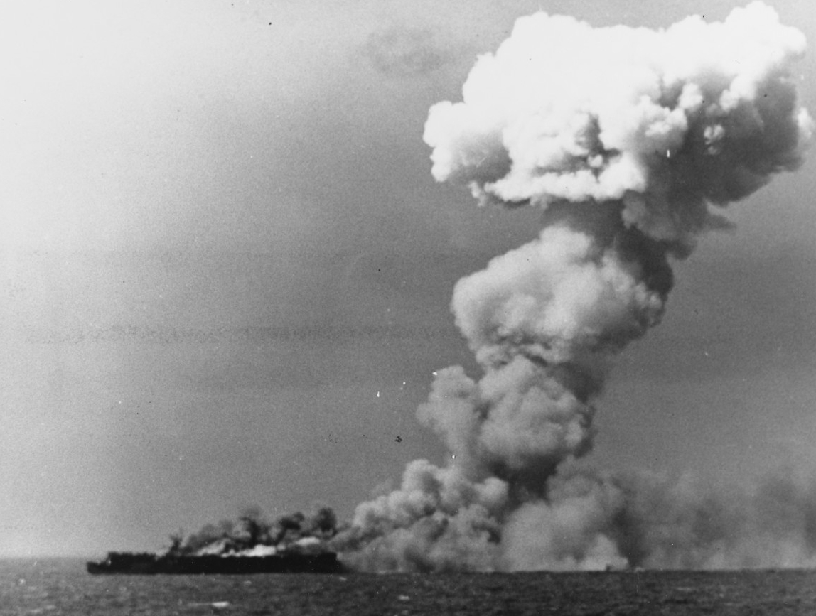 Princeton burns as some of the torpedo warheads in her hangar cook off in a horrific explosion, a huge column of smoke rising from the ship, 24 October 1944. A photographer on board South Dakota snaps this picture, most likely just after the firs...