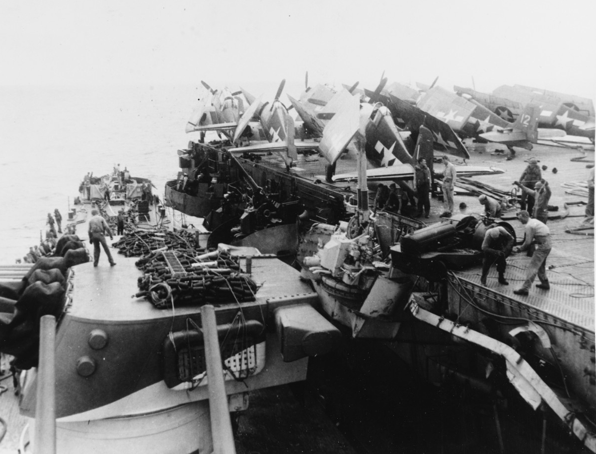 Birmingham (left) helps Princeton (right) during her ordeal, 24 October 1944. The two ships grind together in the swells, and the cruiser’s starboard side crushes part of the carrier’s portside catwalk and a 40-millimeter gun mount. A flight deck...