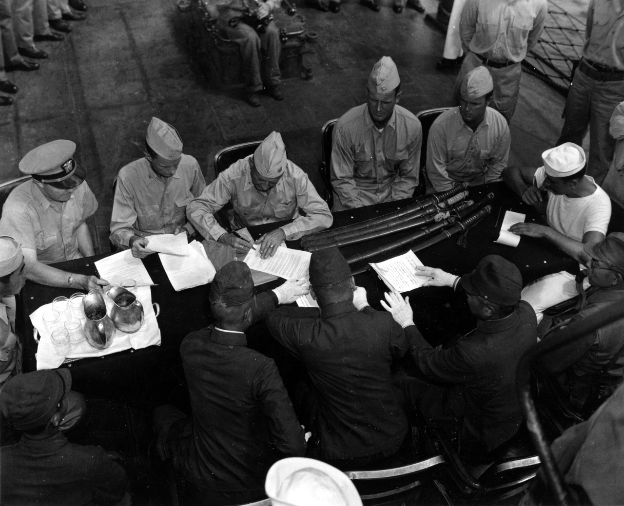 Seated at the table on board Rhind at which the surrender documents for Pagan Island are being signed are (L-R): TSgt. N. Furuiye (U.S. Army interpreter), Cmdr. A. A. Allen, Capt. John C. Hammock, Como Vernon F. Grant, Cmdr. George T. Baker, Lt. ...