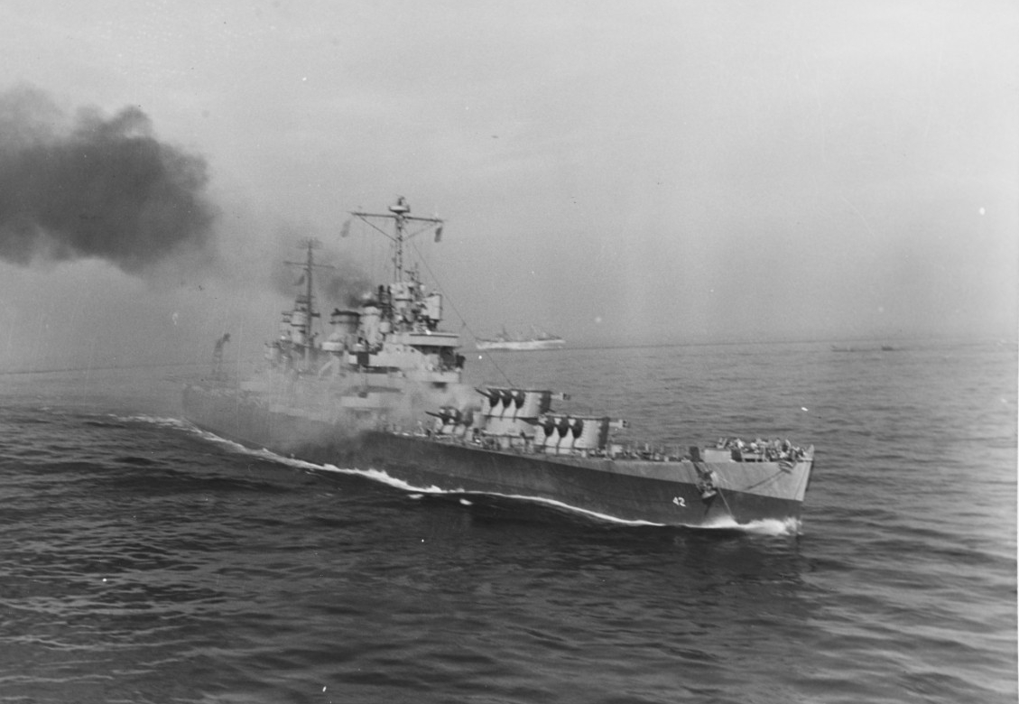 This starboard bow shot taken moments later shows that the ship still has way on, and her turrets are trained toward shore. Smoke billows from the stricken cruiser and she already lists slightly to port. (U.S. Army Signal Corps Photograph SC 2436...