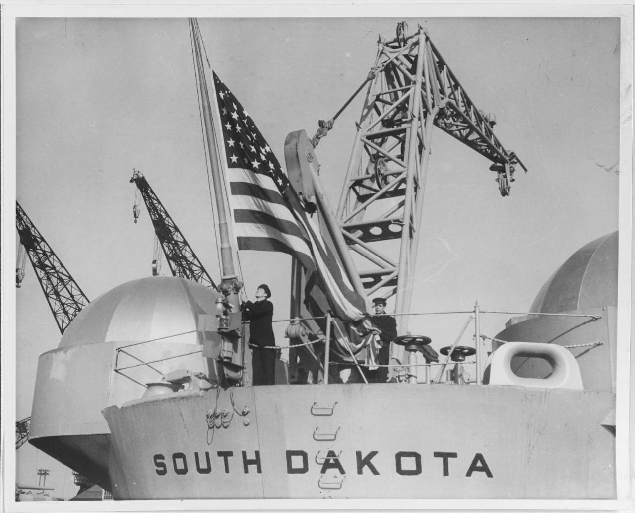 Sailors haul down the colors as South Dakota decommissions at Philadelphia Naval Shipyard, Pa., on 31 January 1947. (U.S. Navy Photograph NH 73929, Naval History and Heritage Command)