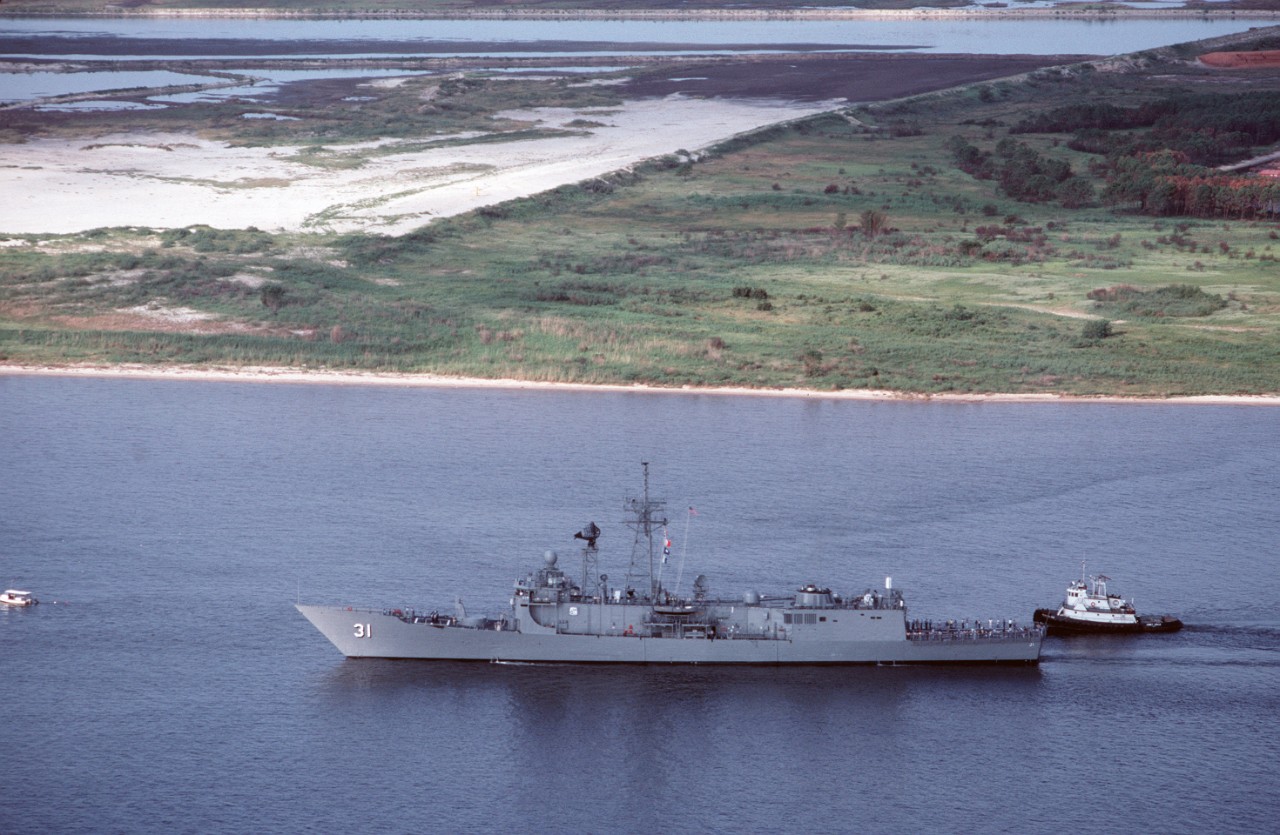 A tug stands by to assist Stark as the frigate resolutely returns to sea for her trials, following the yard work at Pascagoula, Miss, 28 August 1988. The reworked and painted superstructure and hull on the port side indicate the amount of work ac...