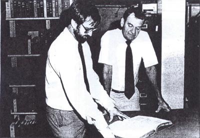 "Inside the stacks, John Vajda (right) assistant librarian (later Library Director] and Dale Sharrick, circulation librarian, peruse an 18th century manuscript. The rare book collection is part of the 200,000 volume Navy Department Library, estab...