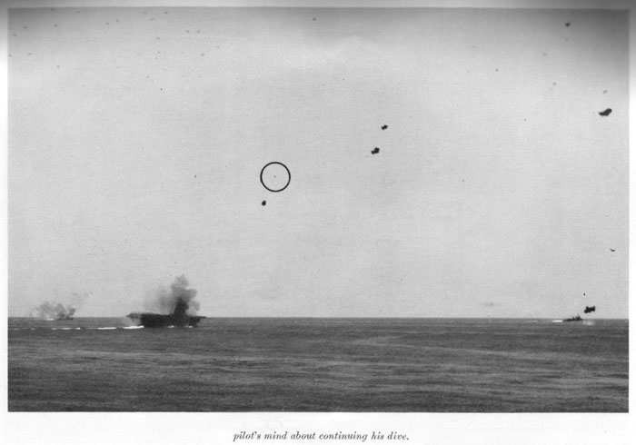 Japanese plane turning away after having started dive on carrier. Large black bursts are 5" shells, and close bursts probably changed pilots mind about continuing his dive.