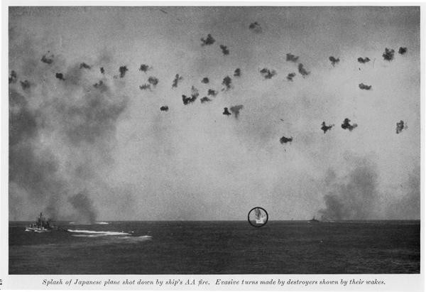 Splash of Japanese plane shot down by ship's AA fire. Evasive turns made by destroyers shown by their wakes.
