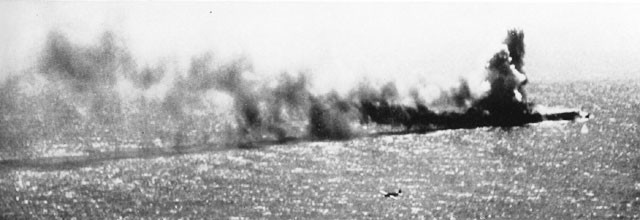 Two of our torpedo planes maneuver in for the kill as the heavily dive-bombed Shoho goes to destruction in smoke and flames.