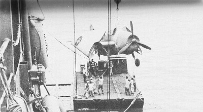 Image of U.S.S. Kitty Hawk at Pallikulo Bay, New Hebrides, unloading torpedo plane to self-propelled 50-ton barge. 