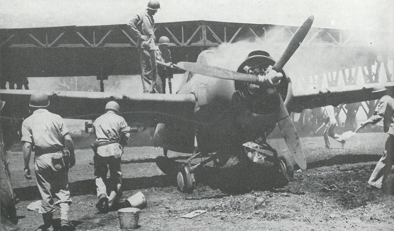 MARINE FIGHTER PLANES fell victim to many mishaps. This MAG-23 F4F-4 is being saved by bucket-brigade methods. Note bullet-pierced propeller blades.