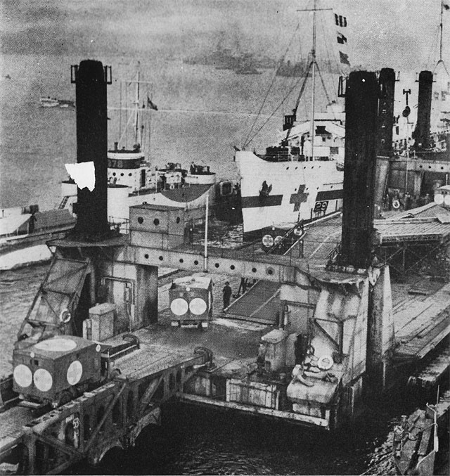 The pierhead in action. Wounded are being transferred from the ambulances to a hospital ship for return to England.