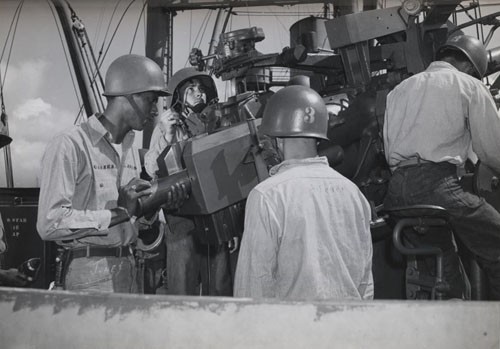 "Ready for action, this gun's crew includes a Negro Gunner's Mate striker who has been aboard this ship in the Pacific only a short time but is doing excellent work. He is Earl Jones, Seaman First Class, shown at the left. Others in the picture are Francis Devitis, Seaman First Class, Chief Gunner's Mate Clyde Scheuer, and Joseph Schiavo, Gunner's Mate Third Class."
