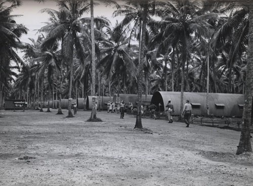 "'Among the Navy men in the New Hebrides' - Members of a navy base company of enlisted Negroes keep the wheels humming at a Navy Base on Espiritu Santo in the New Hebrides. Putting their varied talents into effect, they include within their ranks motor machinist's mates, boatswain's mates, signalmen and storekeepers. Photo shows Main street at Base Camp Annex. Back of bulletin board is the Mail Hut."