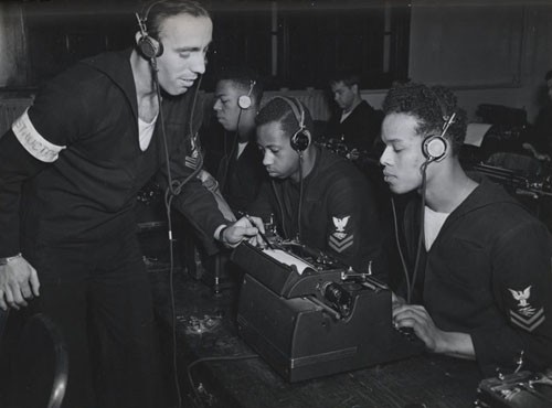 "Receiving and typing off messages, just as they'll be doing when the destroyer escort goes to sea, Radioman Second Class James W. Graham, (right), Radioman Second Class Wendell P. McMillan, and Radioman Third Class Alfred G. Mathis, get pointers at Norfolk NOB [Naval Operating Base] from instructor Radioman Second Class Charles G. Pelham, USN. 