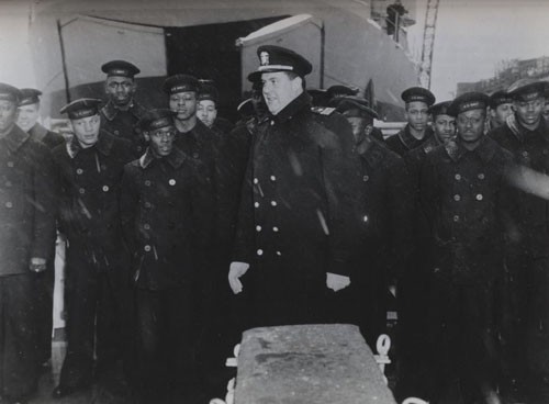 "Skipper and some of the Negro sailors of the USS Mason - destroyer escort, first US Naval vessel with a predominantly Negro crew, at the ship's commissioning ceremony this afternoon at Boston Navy Yard. Lieutenant Commander William M. Blackford, USNR, who assumed command of the vessel and his men smile despite driving snow. 
