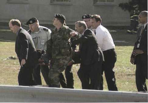 Secretary Rumsfeld (foreground, second from right) assists with carrying a victim on a stretcher toward an ambulance on Route 27.