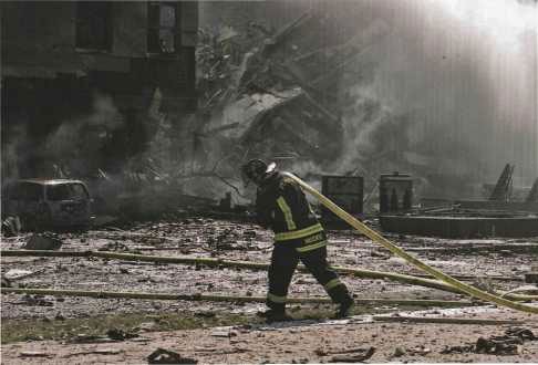 Fort Myer firefighter Vance Valenzo carries a hose across the debris-covered Helipad.