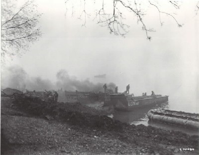 Loading equipment on US Navy LCVP landing craft to be ferried across the Rhine River in Germany, 26 March 1945. Army forces involved are from the 87th Division, Third Army. Note inflatable pontoon at right