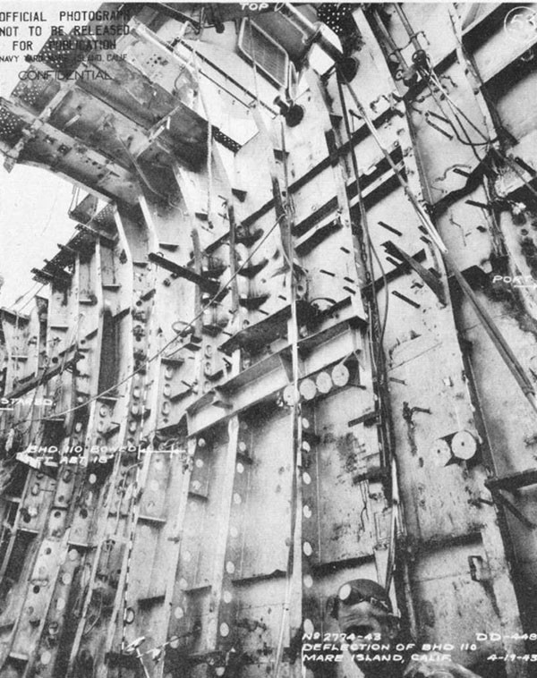 Photo 25: Bulkhead 110 after removal of debris from forward engineroom; deflection due to torpedo blast and static water head.
