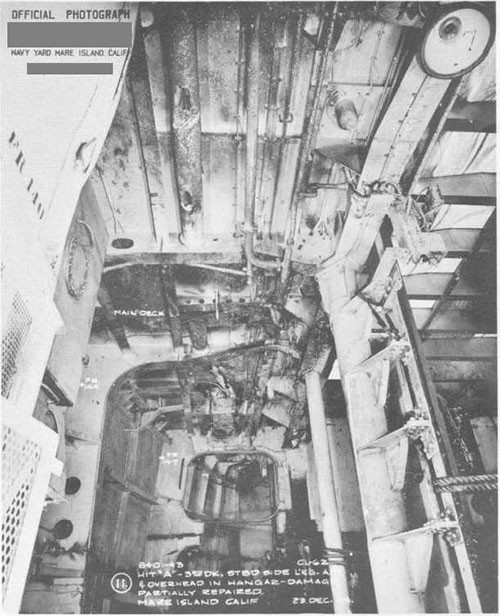 Photo 7: Bomb damage to stern. Looking aft and to overhead in Hangar. Damage partially repaired.