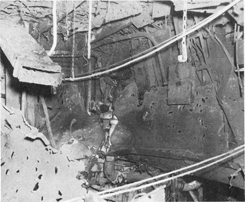 Photo E-4: First hit. Bomb hole in second deck, compartment D-203-1LM. Note fragment holes.