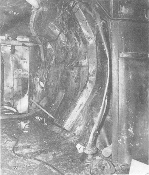 Photo E-7: First hit.  Compartment D-303-1L looking aft showing starboard bulkhead of No.3 elevator pump room (D-523-T) dished in to port, third deck dished down and second deck dished up.