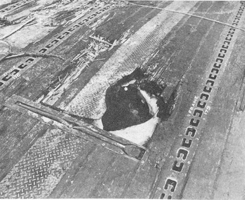 Photo E-13: Second hit. Entrance hole in flight deck made by bomb.