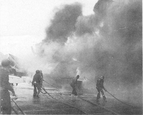 Photo H-4: "Friendly" shell hit. Parked planes on fire. Note use of low velocity fog applicator to protect man with foam hose.