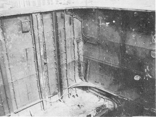 Photo J-6: View looking to port and forward in No. 1 elevator trunk after debris cleared up. Note dishing of bulkheads and fragment holes.