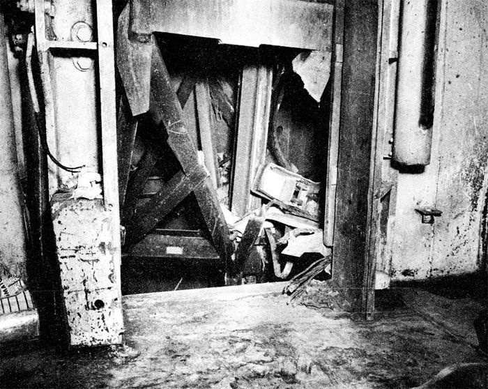 Photo 9: 30 October Action. View showing damaged bomb elevator, B-0435-T, and damaged watertight door 3-128-1 as seen from B-318-L, crew's galley, looking forward.
