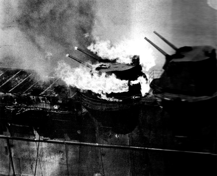 Photo 19: 19 March Action. Ammunition in No. 7 twin mount is burning. This occurred late in fire. Note that fire on flight deck aft is about out.