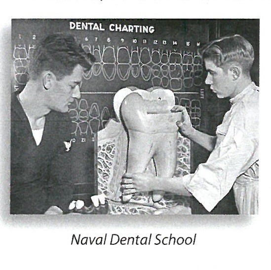 jpeg photo titled "Naval Dental School." that shows two men looking at a model of a gigantic tooth. "Dental Charting" is written on the chalkboard behind them.