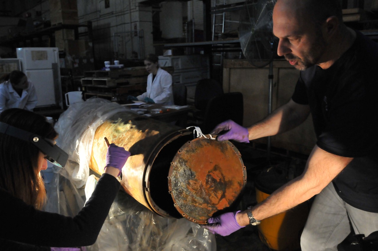 Conservators removes the seal on the mid-section of the Howell Torpedo.